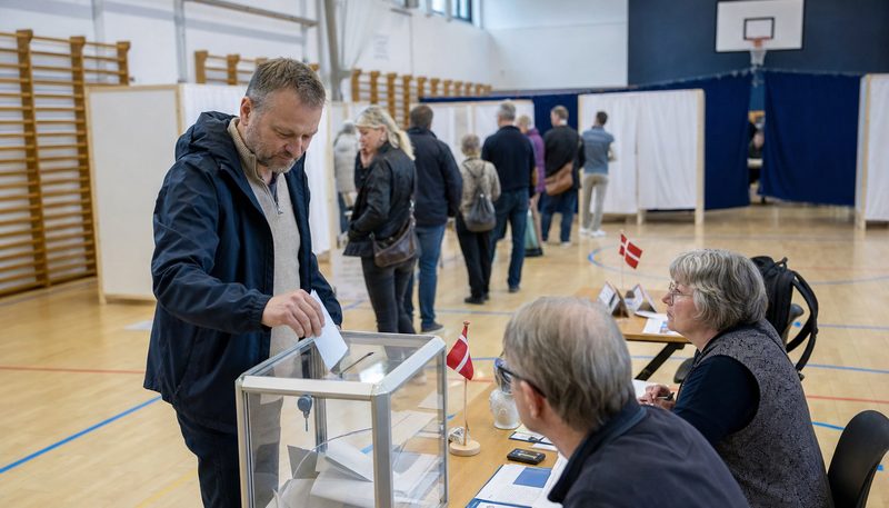 A voter placing a ballot in a transparent ballot box at a Danish polling station on European election day (AI-generated image)