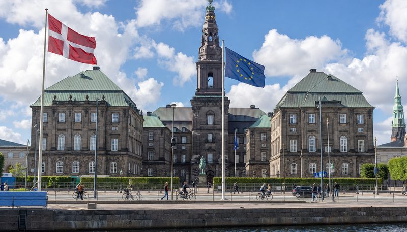 Christiansborg Palace in Copenhagen with the Danish and European Union flags flying in front (AI-generated image)